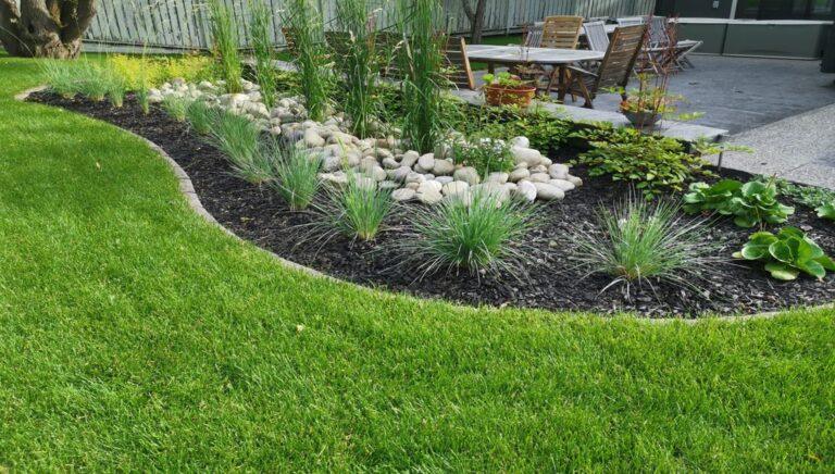 Charcoal mulch garden bed with river rock, lush plantings